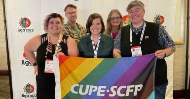 People holding a CUPE 2LSGBTQ+ flag